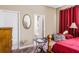 Bedroom with connecting bathroom, wood bed frame with red bedding, a work area, and neutral color palette at 969 Springs Landing Dr, Deltona, FL 32725
