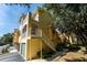 Beautiful yellow townhouse with a staircase leading to a balcony and well-kept landscaping at 12106 Poppy Field Ln # 107, Orlando, FL 32837