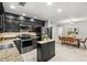 Modern kitchen with black cabinetry, stainless steel appliances, granite countertops, and adjacent dining area at 126 Duncan Trl, Longwood, FL 32779