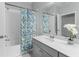 Bright bathroom with white countertops, gray vanity, and a tub with colorful shower curtain at 13227 Spring Grove Way, Winter Garden, FL 34787