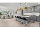 Open kitchen with gray cabinets, white countertops, an island with seating and gold pendant lighting overlooking the dining room at 13227 Spring Grove Way, Winter Garden, FL 34787