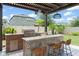 Beautiful outdoor kitchen under a pergola with stainless steel grill, tiled bar, and pendant lights at 13227 Spring Grove Way, Winter Garden, FL 34787
