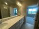Bathroom featuring dual vanities, a glass-enclosed shower, and a serene view of the adjacent bedroom at 1411 Mount Royal Dr, St Cloud, FL 34771