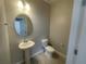 Stylish half bathroom featuring a pedestal sink, mirror, and modern toilet, perfect for guests at 1411 Mount Royal Dr, St Cloud, FL 34771