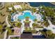 Aerial shot of a clover-shaped pool and cabanas surrounded by palm trees, lounge chairs, and lush landscaping at 1505 Nassau Point Trl, Kissimmee, FL 34747