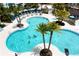 Aerial view of a large pool with people swimming, surrounded by palm trees, cabanas, and lounge chairs at 1505 Nassau Point Trl, Kissimmee, FL 34747