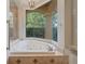 Large soaking tub with jets by a large window with backyard views and chandelier at 1542 Islay Ct, Apopka, FL 32712