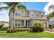 Two-story gray home with a well-maintained lawn, tropical landscaping, and a brick driveway to the attached garage at 2431 Tudor Rose Dr, Sanford, FL 32773