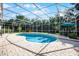 Screened pool area features a kidney-shaped pool, brick paver deck, and table with umbrella, surrounded by mature trees at 2487 River Tree Cir, Sanford, FL 32771