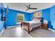 Bedroom with bright blue walls, wood-look floors, large window and TV at 283 Lakay Pl, Longwood, FL 32779