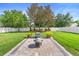 Large backyard featuring lush green grass, an outdoor fire pit, and mature trees at 3551 Statham Dr, Apopka, FL 32712