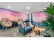 Cozy living room features a pink sunset mural, plush seating, and tropical plants creating a relaxing retreat at 4161 Paragraph Dr, Kissimmee, FL 34746