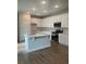 Modern kitchen features white cabinets, stainless steel appliances, an island with sink, and tile backsplash at 446 Scotsmans Pl, Debary, FL 32713