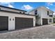 Attached three-car garage, with dark doors and stone-paved driveway, on this modern two-story white home at 523 W Princeton St # 1, Orlando, FL 32804