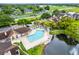 Aerial view of a community pool near a pond, surrounded by mature trees and green lawns at 5545 Devonbriar Way # 206, Orlando, FL 32822