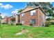 Exterior view of townhouse with brick facade, green grass lawn, trimmed bushes, and flowering tree in a common area at 5545 Devonbriar Way # 206, Orlando, FL 32822