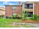 Exterior view of a red brick and brown siding condo unit with lush landscaping at 5545 Devonbriar Way # 206, Orlando, FL 32822