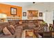Comfortable living room with a large brown sectional sofa, decorative pillows, and orange accent wall with stylish decor at 5545 Devonbriar Way # 206, Orlando, FL 32822