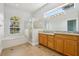 Bright bathroom features a tub, standing shower, dual sinks, wood cabinets and a large window at 604 Cheviot Ct, Apopka, FL 32712