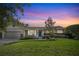 Charming single-story home with a well-manicured lawn and inviting curb appeal under a gorgeous sunset sky at 676 Dunblane Dr, Winter Park, FL 32792