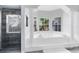 Bright bathroom with a large soaking tub, a separate glass shower, and views of the surrounding greenery at 718 Glen Eagle Dr, Winter Springs, FL 32708