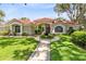 Charming home with a beautiful red tile roof, lush lawn, landscaped yard, and inviting walkway leading to the front door at 718 Glen Eagle Dr, Winter Springs, FL 32708