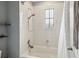 Bright bathroom features a shower and tub combination with white tiled walls and a window at 731 Arbor Pointe Ave, Minneola, FL 34715
