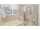 Bathroom features a tub/shower combination with a glass enclosure and a travertine tile surround at 7650 Whisper Way # 104, Reunion, FL 34747