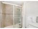 Bathroom with a tile shower featuring a glass door and towel rack at 7650 Whisper Way # 104, Reunion, FL 34747