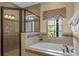 Bright bathroom features a tile-enclosed shower, a bathtub, and a window with exterior views at 796 Desert Mountain Ct, Reunion, FL 34747