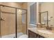 Well-maintained bathroom featuring a shower with glass doors, dark wood vanity, granite countertops, and a window at 796 Desert Mountain Ct, Reunion, FL 34747
