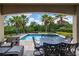 Covered patio space with comfortable seating and outdoor dining, overlooking the pool and beautiful landscaping at 796 Desert Mountain Ct, Reunion, FL 34747