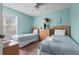 Tranquil blue bedroom featuring two twin beds, a ceiling fan, and a bright window for plenty of natural light at 8507 Crystal Cove Loop, Kissimmee, FL 34747