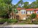 Inviting two-story townhome with a terra cotta roof, lush landscaping, and tall palm trees, creating a welcoming curb appeal at 8507 Crystal Cove Loop, Kissimmee, FL 34747