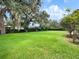 A well-manicured backyard with green grass, mature trees, and privacy hedges at 8531 Cypress Hollow Ct, Sanford, FL 32771