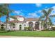 Stunning two-story home featuring a red tile roof, arched entryway, and meticulously manicured landscaping with palm trees at 8531 Cypress Hollow Ct, Sanford, FL 32771
