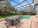 Screened-in patio features brick pavers, outdoor dining set, and a sparkling swimming pool with water feature at 8531 Cypress Hollow Ct, Sanford, FL 32771