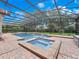 A screened-in pool and spa surrounded by a brick patio and lush landscaping, perfect for entertaining or relaxation at 8531 Cypress Hollow Ct, Sanford, FL 32771