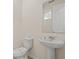 Bright bathroom with a pedestal sink, standard toilet, and framed mirror at 8928 Coconut Breeze Dr, Kissimmee, FL 34747