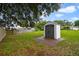 Backyard shed sitting on a concrete pad, surrounded by a grassy lawn and trees at 1447 Candlewyck Dr, Orlando, FL 32807