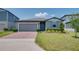Charming single-story home featuring a well-manicured lawn, brick driveway, and a cozy, inviting entrance at 17363 Million Lakes Ct, Clermont, FL 34714