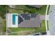 Aerial view of home with solar panels and pool with travertine surround, privacy fence, and lush green grass at 1740 Standing Rock Cir, Oakland, FL 34787