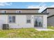 A backyard featuring a sliding glass door, two windows, and an efficient air conditioning system at 1797 Archer Dr, Minneola, FL 34715