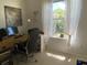 Bright office space featuring a wood desk, black chair, and natural light from a window with sheer curtains at 19430 Sw 100Th Loop, Dunnellon, FL 34432