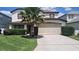 Inviting home showcasing a well-manicured lawn, mature palm tree, and a two-car garage at 226 Canna Dr, Davenport, FL 33897