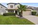Charming two-story home with a well-manicured lawn and a mature palm tree in the front yard at 226 Canna Dr, Davenport, FL 33897