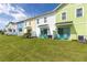 Backyard featuring a lush green lawn, blue Adirondack chairs and brightly painted townhomes at 2923 Castaway Ln, Kissimmee, FL 34747