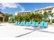 Inviting poolside with blue lounge chairs, palm trees, and resort buildings in the background at 2923 Castaway Ln, Kissimmee, FL 34747