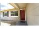 Home entrance with modern red door, shaded porch, and manicured landscaping at 3223 Dragoon Pl, Orlando, FL 32818