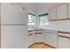 Corner kitchen featuring white appliances and cabinets, wood-look flooring, a double basin sink, and natural light at 324 Sir Lawrence Dr, Sanford, FL 32773